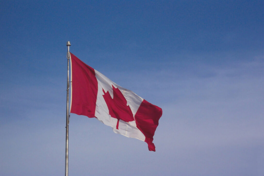 Canadian flag flying against a blue sky