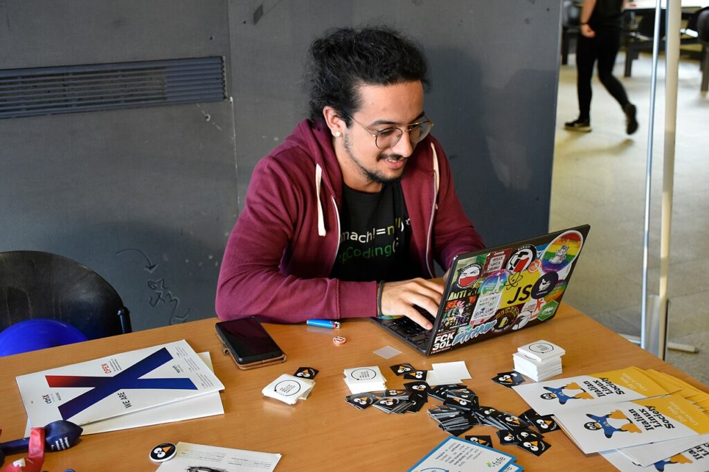 Linux Day Milano attendee using a sticker-covered laptop in 2022