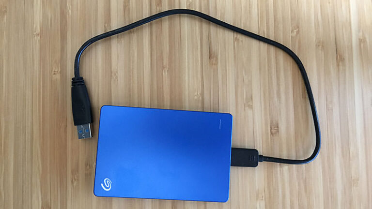 Blue portable external hard drive with an unplugged USB cable on a wooden surface